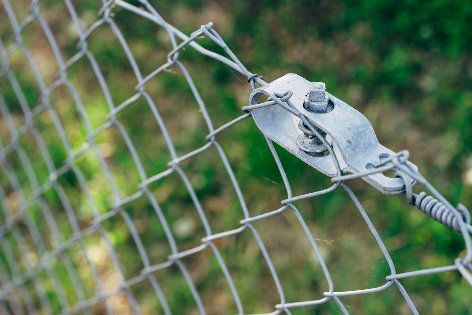 Chain-link fence mesh fixed to a post with a bolted band